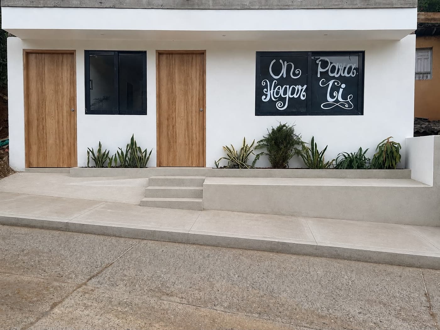 Fachada de día de la casa premio en Urrao, con puertas de madera y jardín