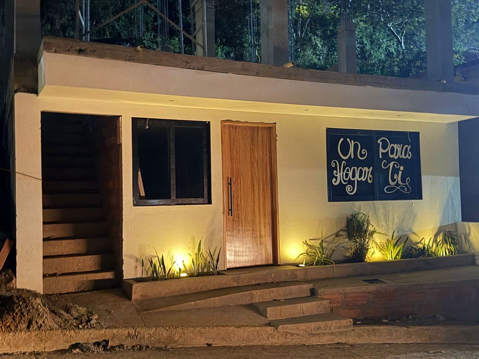 Casa premio en Urrao de noche, con luz cálida y el letrero “Un hogar para ti”