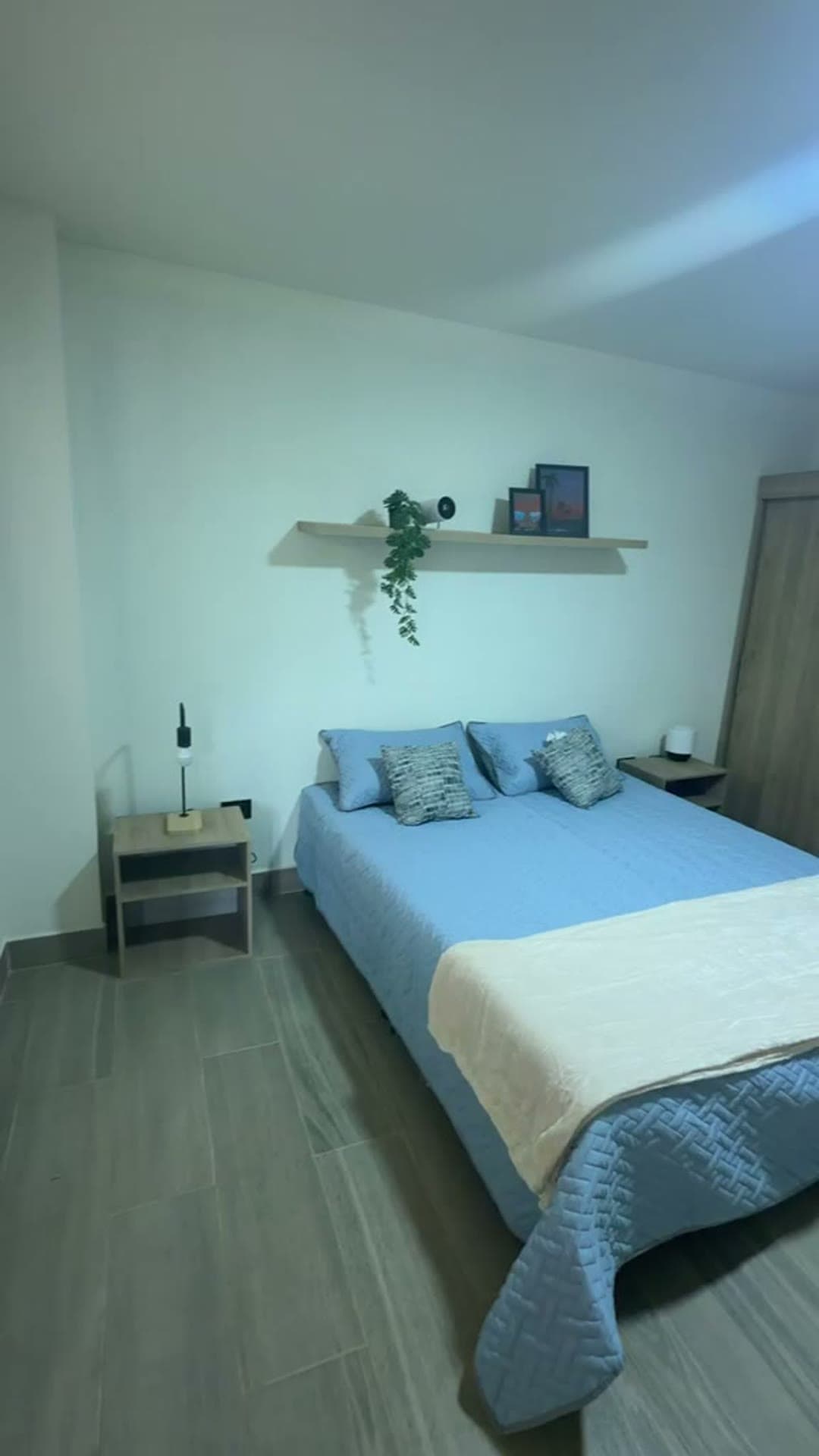 Segunda alcoba con cama azul y mesas de noche